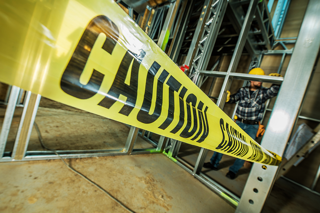 Construction site with caution tape and worker building Bud Board Dispensary location.