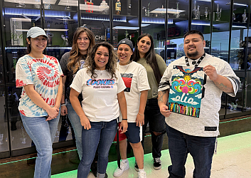 Bud Board Smoke Shop & Dispensary team inside the Canyon Street location in Carlsbad, NM, standing by the glass display.