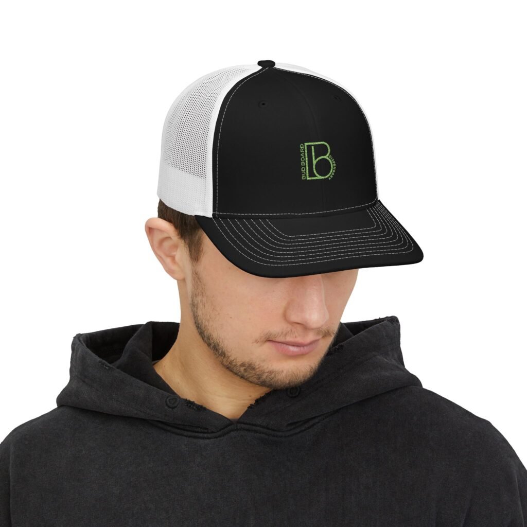 Male model wearing Bud Board Dispensary black and white trucker hat with green logo.
